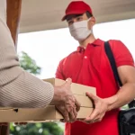 Pizza delivery driver handing pizza boxes to a customer at the door.